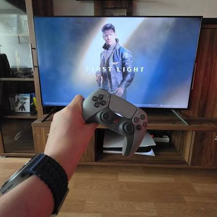 Jogador com comando PlayStation 5 diante da televis&atilde;o