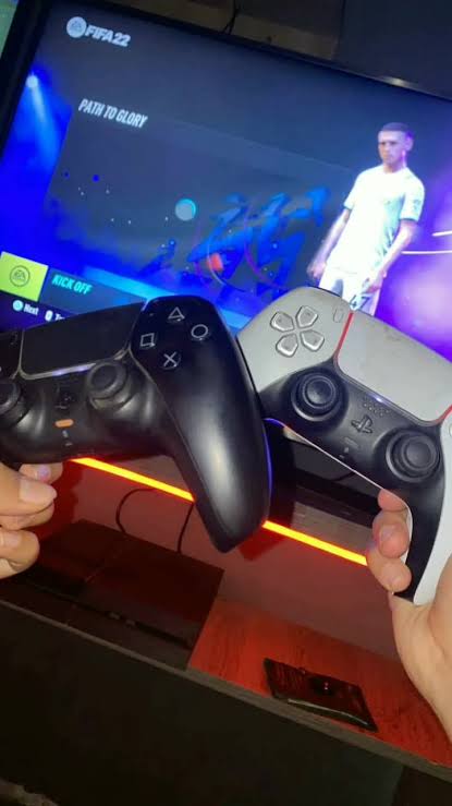 Dois comandos PlayStation durante uma partida de futebol
